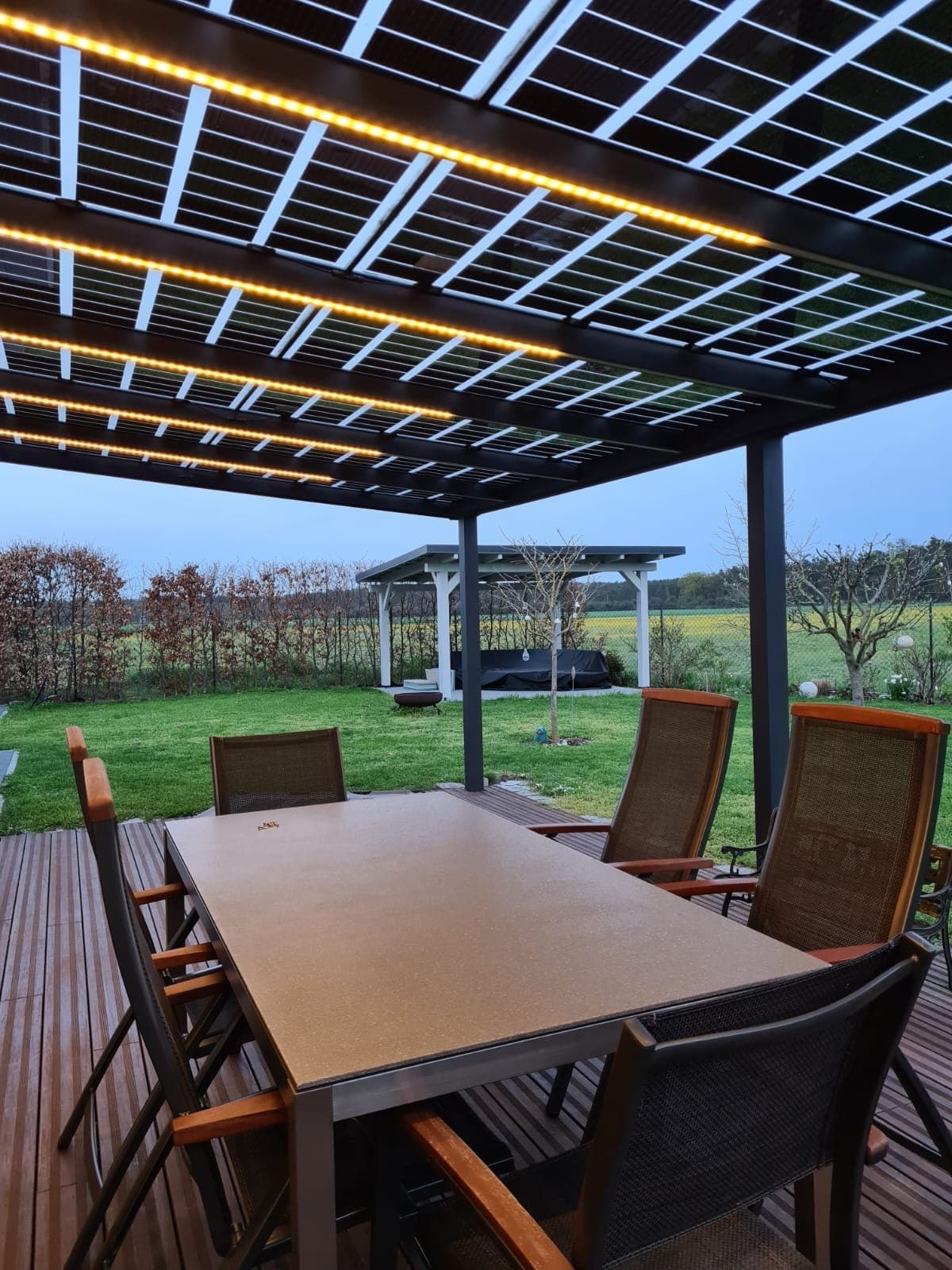Solar-Terrassendach bei Dämmerung mit integrierter LED-Beleuchtung und Sitzbereich